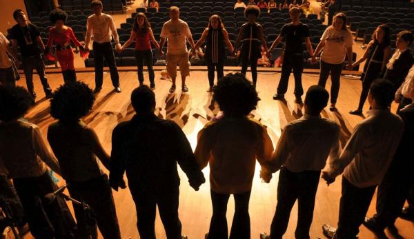 Image of people standing on a stage, holding hands.