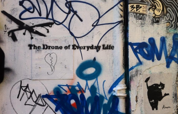 Graffiti on a wall saying "The Drone of Everyday Life"